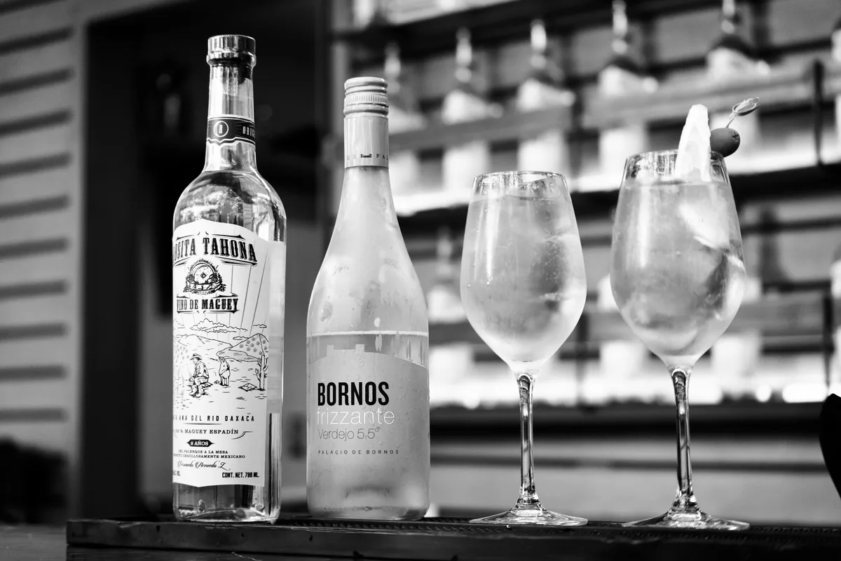 Bottles and glasses of pale Fino sherry on a light background