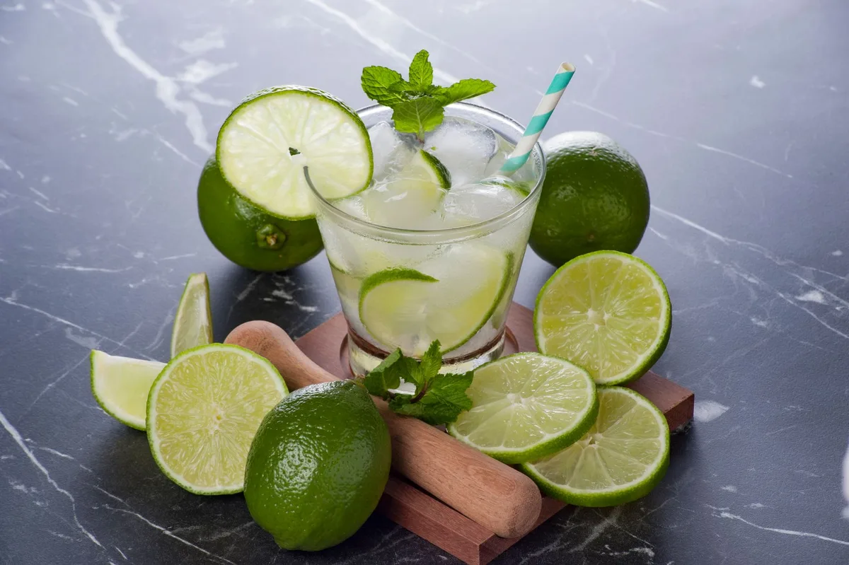 Pale golden sherry cocktail in a glass with crushed ice and fresh lime wedges