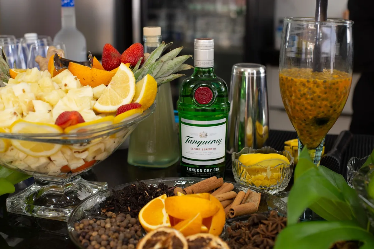 Ingredientes para el cóctel Difford's Fruit Cup No.1: botellas de ginebra, curaçao, vermut y amargos sobre una mesa