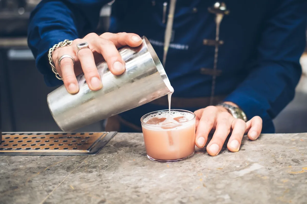 A bartender shaking a cocktail with ice to build foam and chill the mixture
