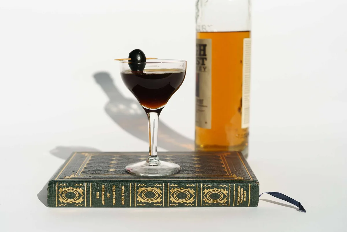 Bottles of apple brandy, sweet vermouth, fernet, and maraschino liqueur arranged on a bar