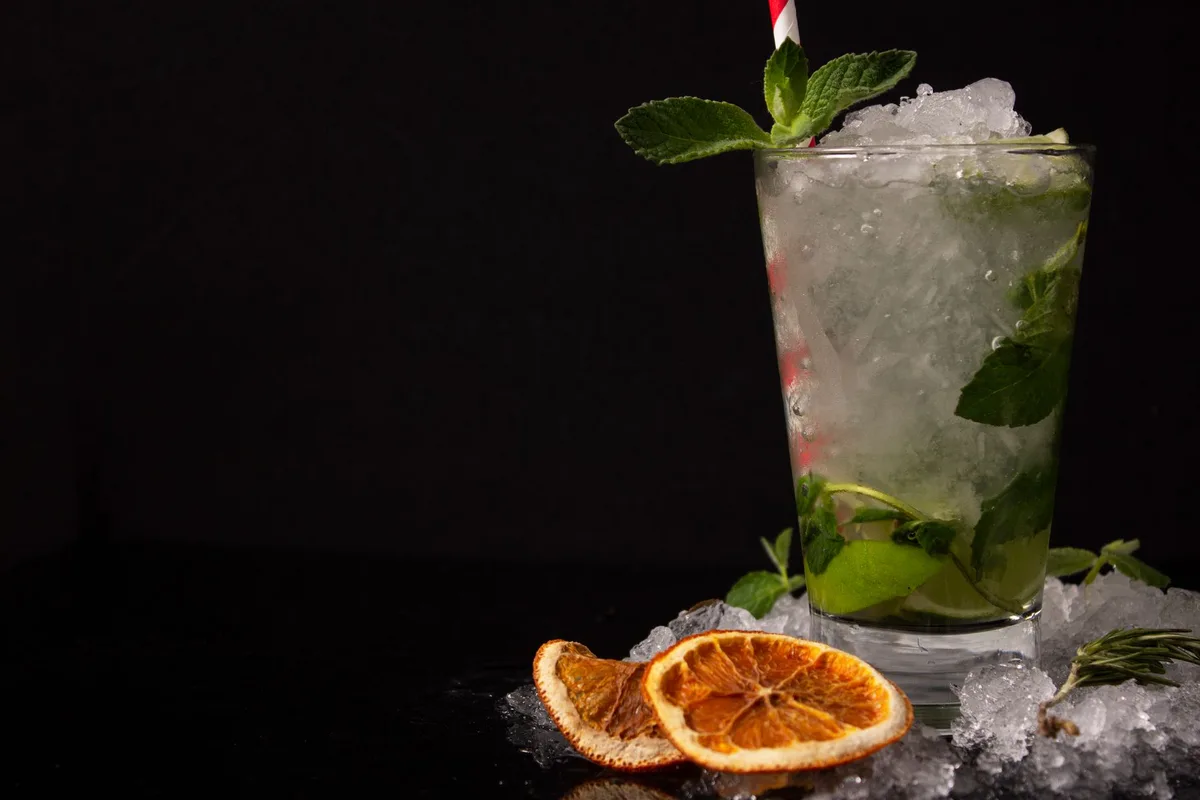 Hands stirring a cocktail with ice in a mixing glass on a bar counter