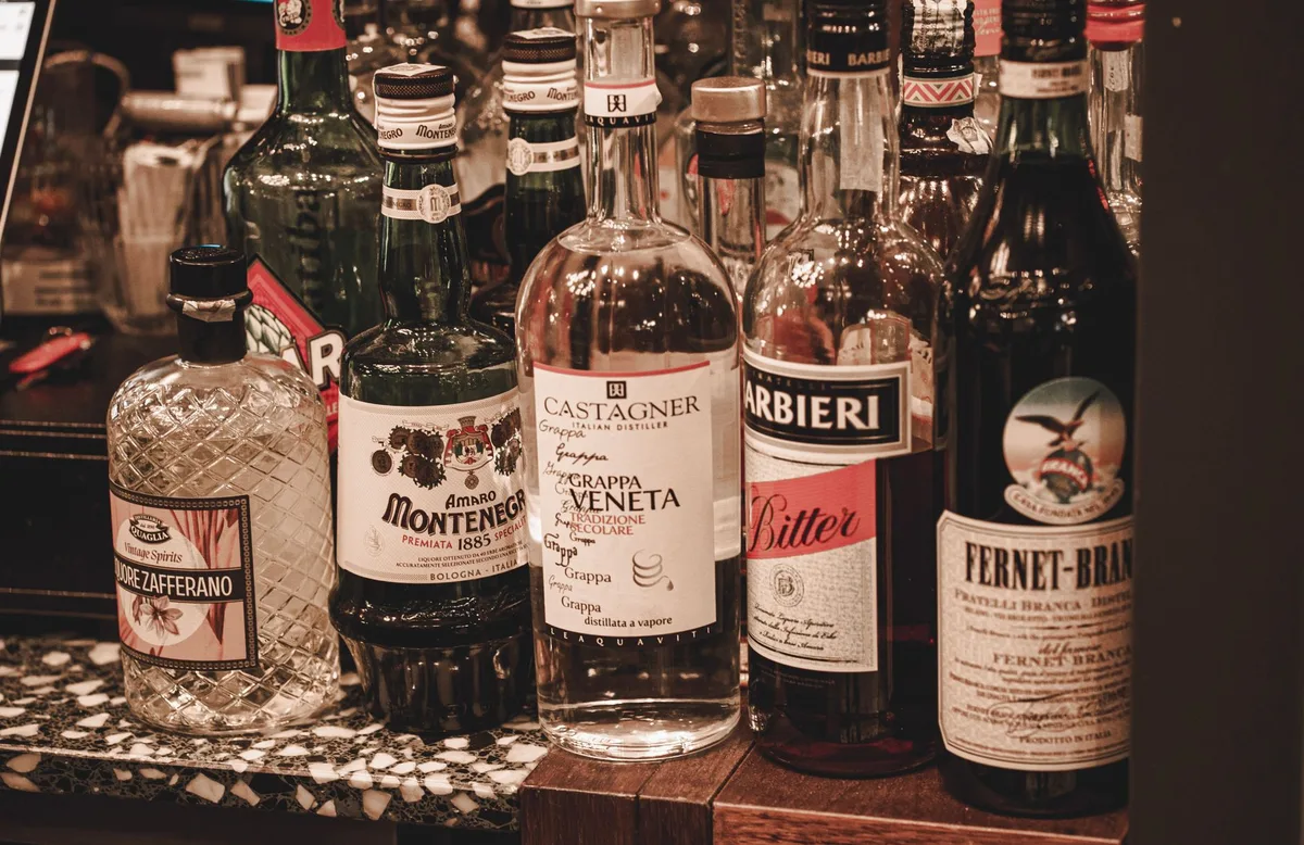 Bottles of gin, amaro, génépy and maraschino liqueur arranged on a bar counter