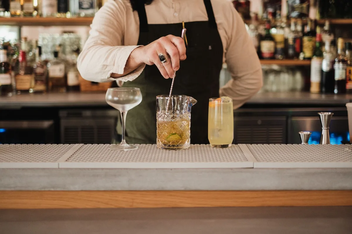 An elegant craft cocktail in an old-fashioned glass with rosemary garnish and ice cube