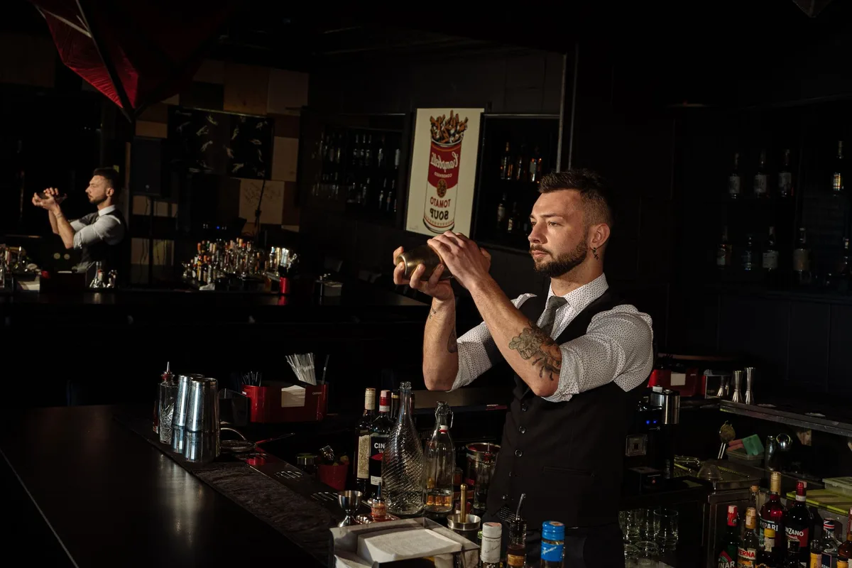 Barman secouant énergiquement un shaker pour créer la mousse du cocktail limoncello sour