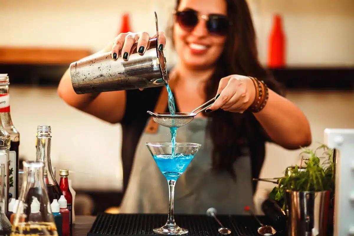 Mixing glass being stirred with ice beside a chilled coupe and lemon twist