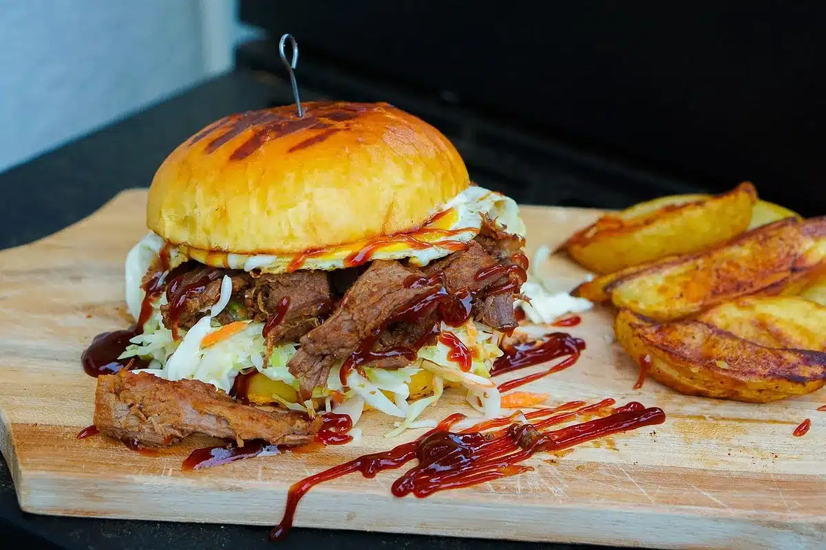 Sheet pan nachos topped with pulled pork, melted cheese and a side bowl of coleslaw