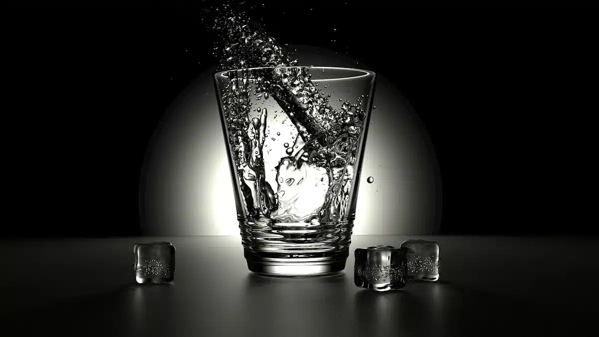 Mixing glass with ice and bar spoon beside a chilled martini glass