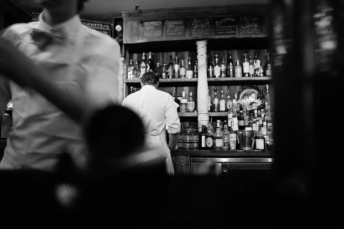 Hands shaking a cocktail shaker near a coupe, ready to double-strain