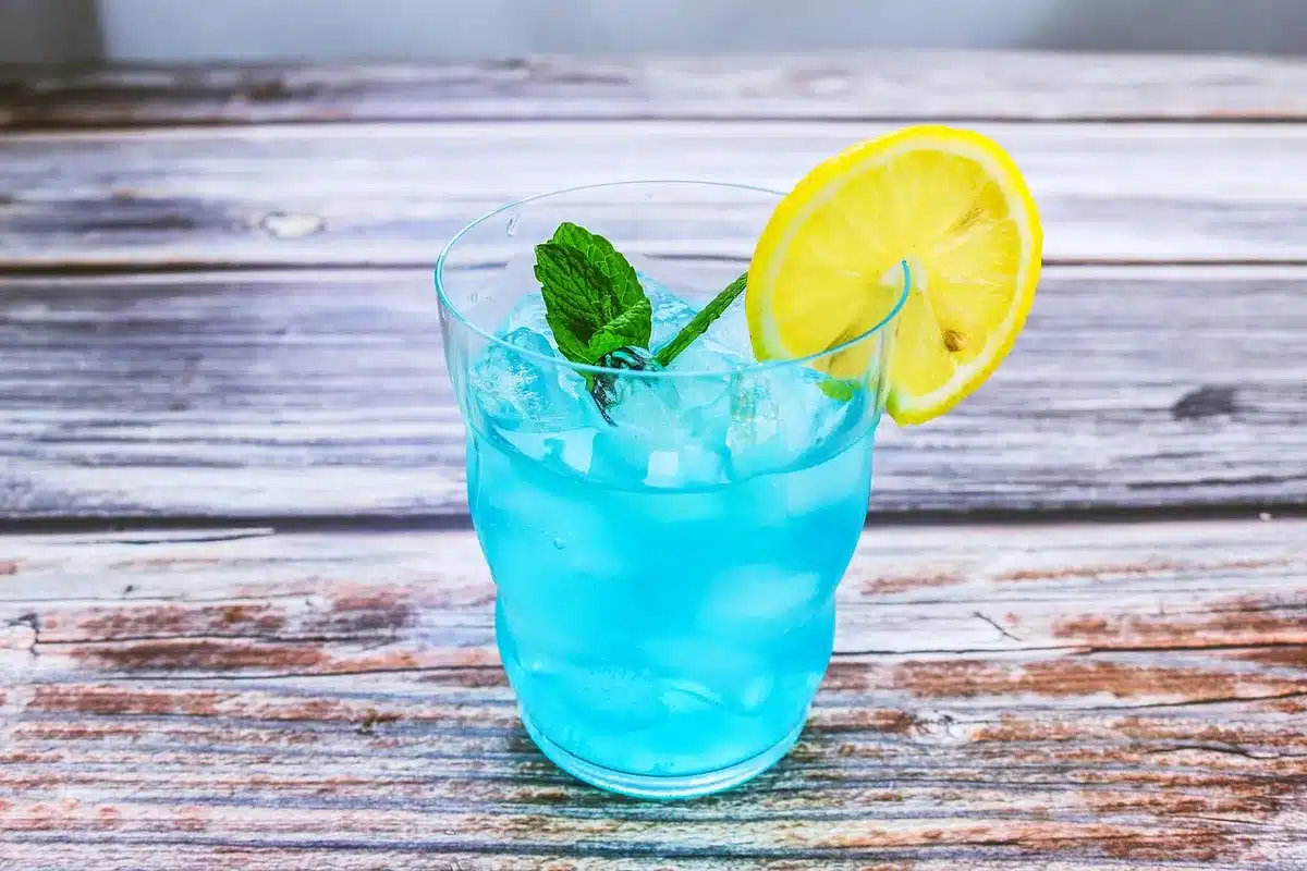 Shaker and crushed-ice filled rocks glass with lime and mint by a sunny window
