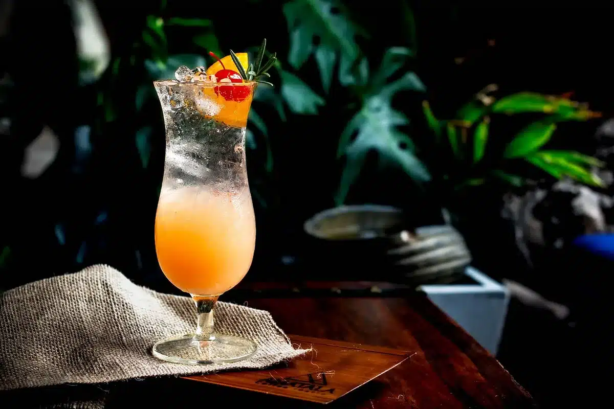 Hands shaking a cocktail shaker over a bar with fresh grapefruit nearby