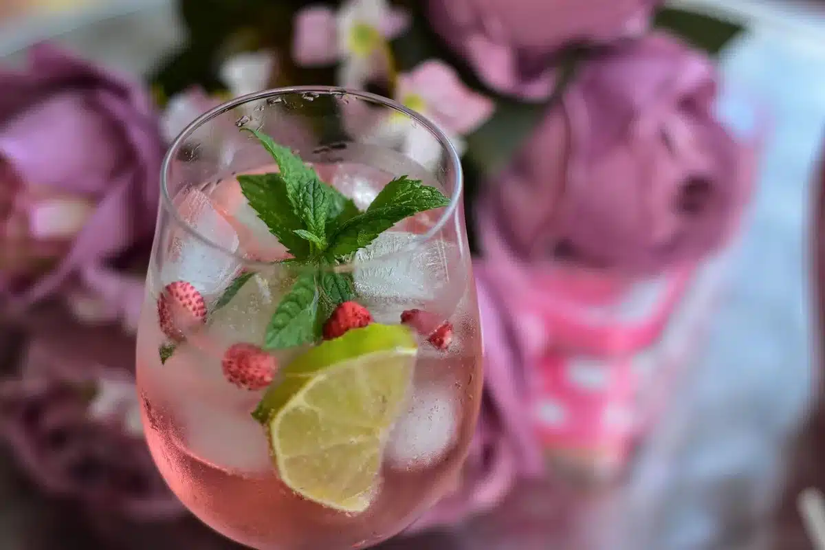 Un barman verse un cocktail depuis un shaker dans un verre highball sur glace