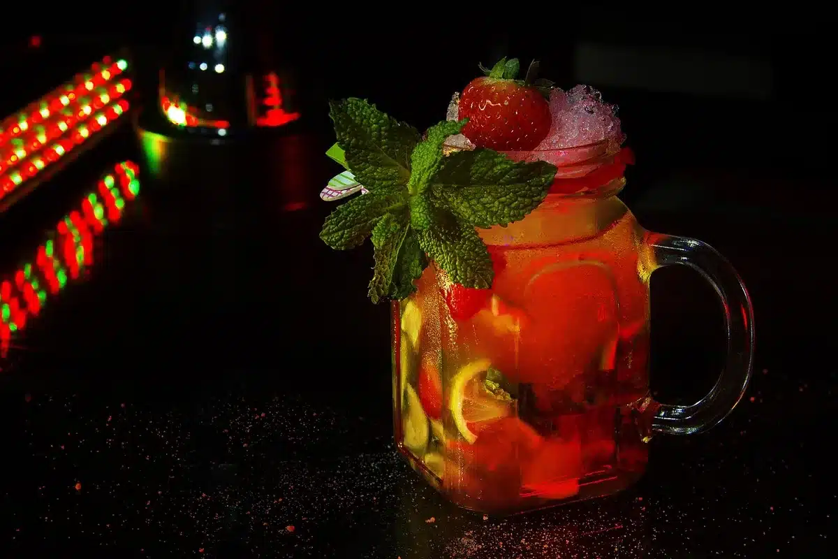 Ingrédients disposés : fraises, tequila, citrons verts et aperitivo sur un plan de travail