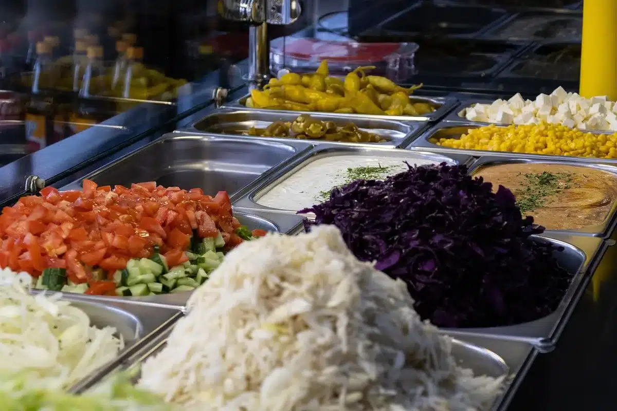 Maines préparant des légumes près d'un bol de nouilles dans une cuisine lumineuse