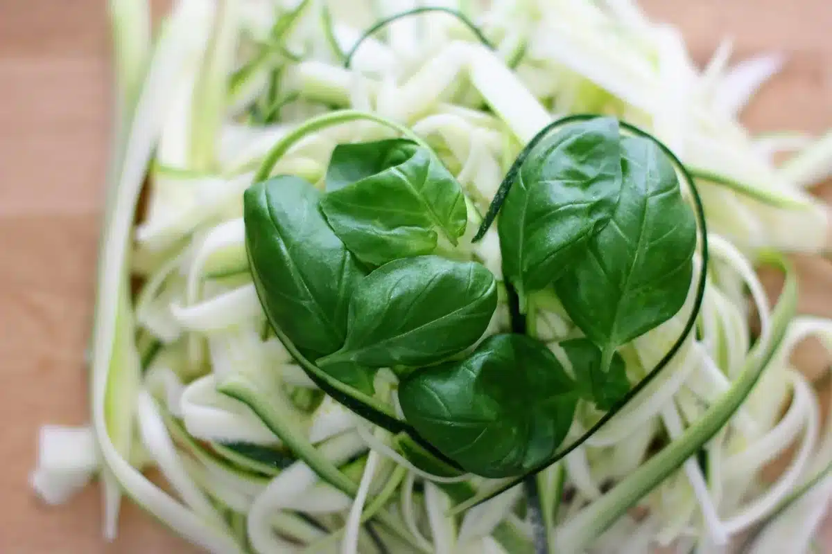 Bowl of zucchini ribbons with creamy lemon-basil sauce on a sunlit kitchen counter