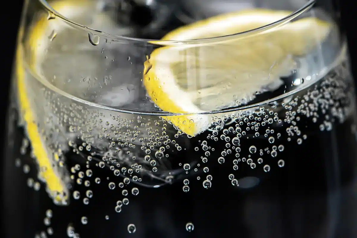 Hands stirring a cocktail in a mixing glass with ice and bar tools