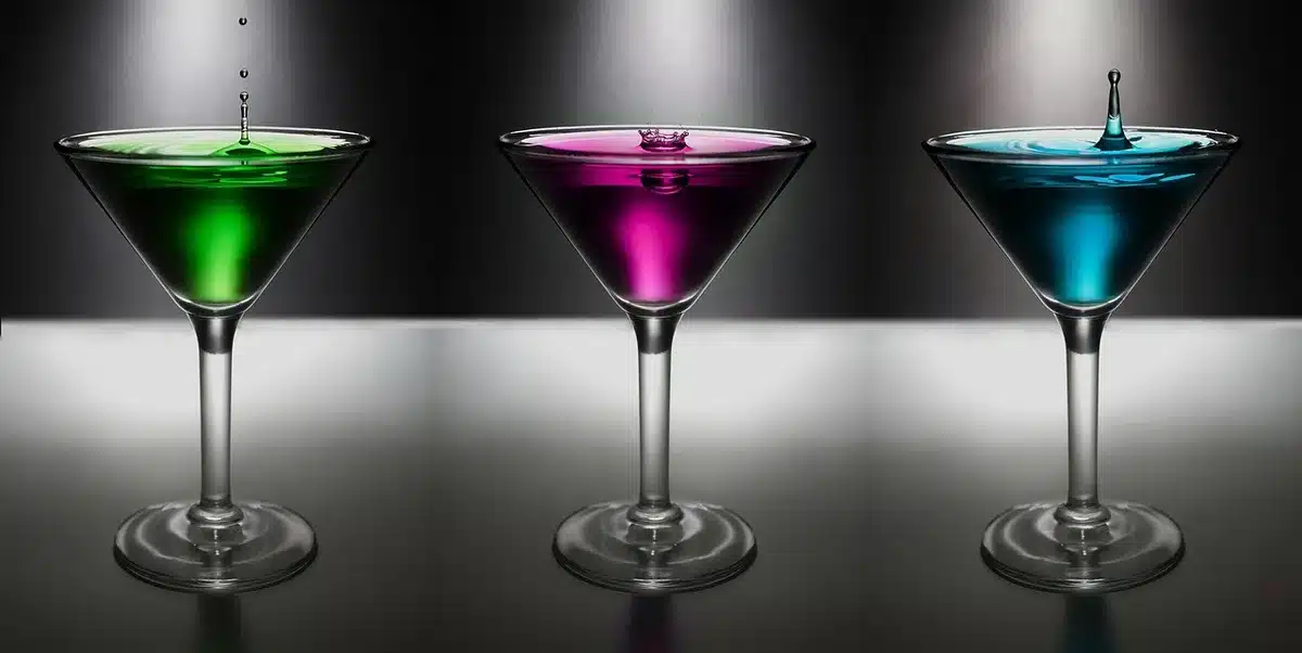 Measured gin, fresh lime and orange liqueur beside blackcurrants and a jigger